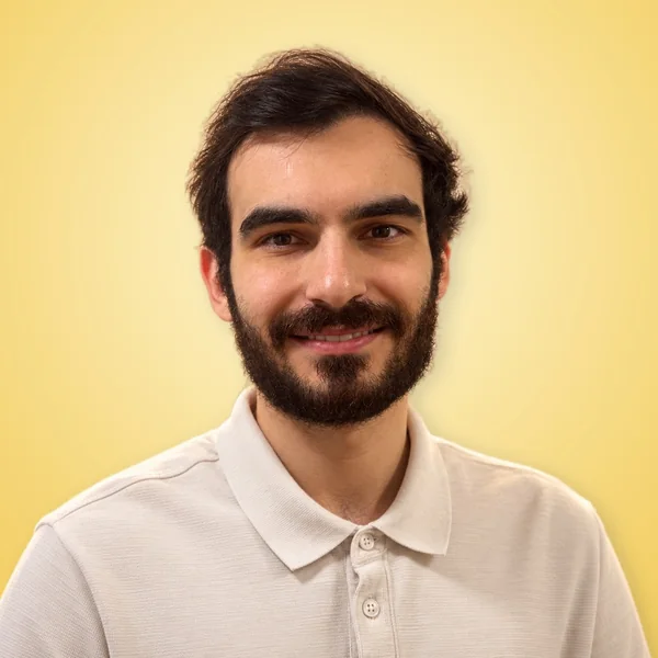 Misha Gurevich sonriendo, sobre fondo amarillo.